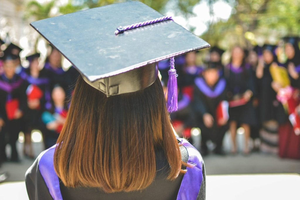 a woman in mortar board and gown in higher education