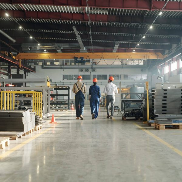 Rear view of three engineers leaving workshop at the end of working day IT løsninger for produksjon og logistikk